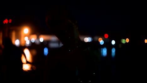 Street-punk-or-hipster-girl-with-pink-dyed-hair.-Woman-with-piercing-in-nose,-lenses,-ears-tunnels-and-unusual-hairstyle-stands-at-night-illuminated-city.