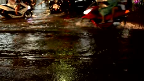 Camino-de-la-inundación-en-lluvia-de-la-noche-caen-con-motos-y-coches-como-fondo