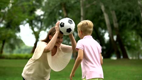 Jungen-Fußball-spielen-mit-Mama-im-Park,-glückliches-Wochenende-mit-der-Familie,-gesunde-Lebensweise