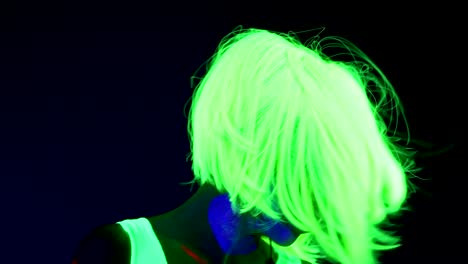 Slow-motion-of-Woman-with-UV-face-paint,-wig,-glowing-clothing-portrait-shaking-her-head.-Caucasian-woman.-.