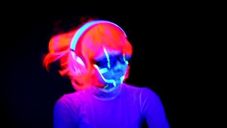 Woman-with-UV-cyborg-face-paint,-wig,-glowing-glasses,-clothing-dancing-and-listening-to-music-with-headphones.-Asian-woman.-.