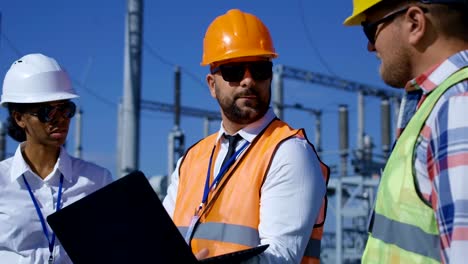 Three-electrical-workers-reviewing-documents-outside