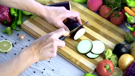 Man-is-cutting-vegetables-in-the-kitchen,-slicing-eggplant