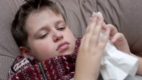 The-boy-blows-his-nose-in-paper-napkins.-He's-got-a-cold