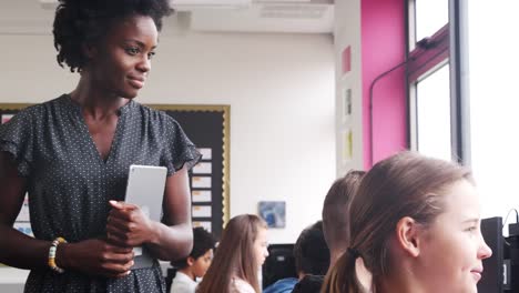 Female-Teacher-Supervising-Line-Of-High-School-Students-Working-at-Screens-In-Computer-Class