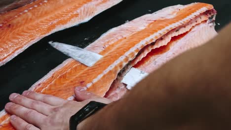 Chef-nimmt-Knochen-vom-Lachs-Filet-schneiden-Fisch-auf-Scheiben-zum-Kochen-Sushi-in-4-k-Auflösung-in-Zeitlupe