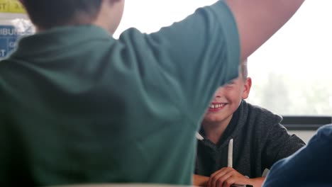 Male-High-School-Students-Sitting-Around-Table-In-Classroom-Answering-Question-During-Lesson