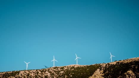 lapso-de-tiempo-de-4-k-de-las-turbinas-del-molino-de-viento-encima-de-gama-de-la-montaña-contra-el-cielo-azul-brillante