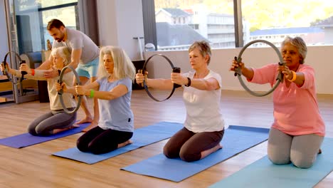 Trainer-assisting-senior-women-in-performing-yoga-4k