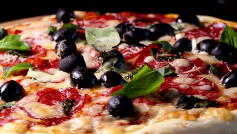 Baked-pizza-with-salami-pepperoni,-black-olives,-basil-and-mozarella-cheese.-Spin-shot.