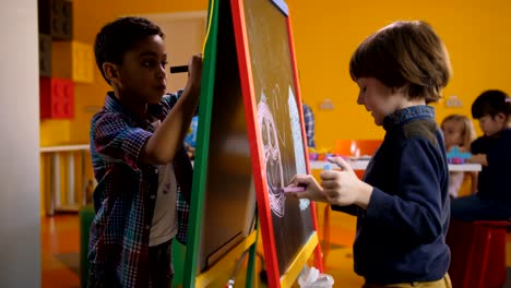 Boys-drawing-with-colorful-chalks-on-easel-board