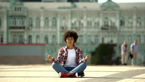 Hermosa-mujer-afroestadounidense-practicando-yoga-en-el-centro-de-la-ciudad,-meditación