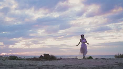 Sensual-joven-con-maquillaje-brillante-en-un-vestido-rosa-bailando-en-la-orilla-del-río.-La-danza-de-una-tierna-chica-con-un-peinado-de-flor.-Cámara-lenta.