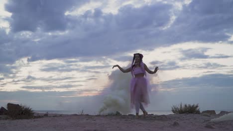 Beautiful-girl-with-sparkling-makeup-in-pink-dress-dancing-in-the-mist-from-smoke-bombs-on-the-bank-of-the-river.-The-dance-of-a-sensual-woman-with-a-flower-hairstyle.-Slow-motion.