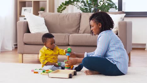 Mutter-und-Baby-spielen-mit-Spielzeugblöcken-zu-Hause