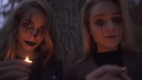 Porträt-von-zwei-Mädchen-mit-Halloween-Make-up-auf-Gesichterhalten-kleine-Kerzen-in-den-Händen-in-der-Kamera-suchen