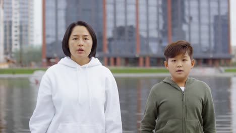 Asian-Mother-and-Son-Drinking-Water-and-Posing-for-Camera-after-Run