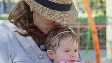 Woman-with-a-baby-in-carrier-kissing-baby's-head