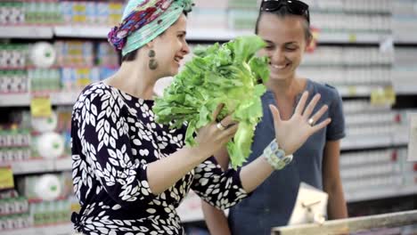 Dos-amigas-seleccionando-lechuga-verde-en-tienda-de-abarrotes