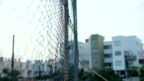 Angry-bald-man-beats-his-hands-on-a-grid-fence.-Aggressive-young-man