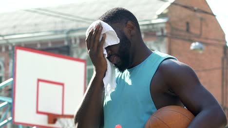 Tired-athlete-wiping-face-from-sweat-after-long-workout-on-sports-ground-slow-mo