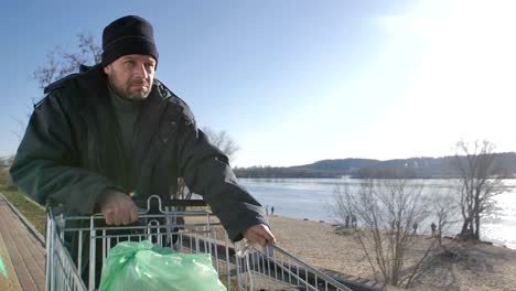 Portrait-of-mature-homeless-man-walking-near-river