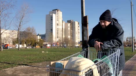 Mature-homeless-man-collecting-plastic-from-trash