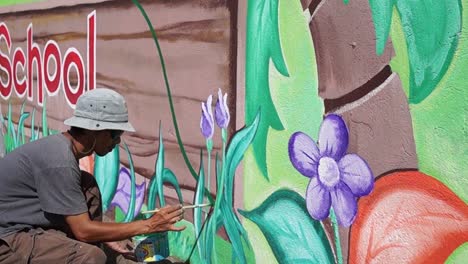 Pintor-mural-dibuja-jardín-en-la-pared-de-la-escuela