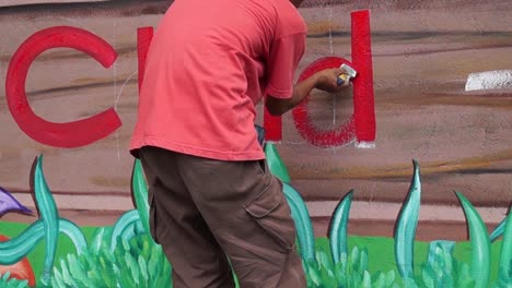 Mural-painter-draws-letter-d-on-school-wall