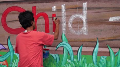 Mural-painter-draws-letter-i-on-school-wall