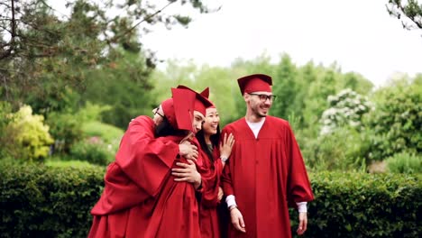 Glückliche-Schüler-umarmt,-hohe-fünf-tun-und-genießen-Draduation-Tag-auf-dem-Campus-mit-schönen-Bäumen-im-Hintergrund-lachen.-Konzept,-Glück,-Jugend-und-Volk.