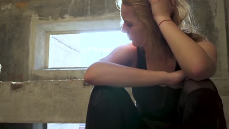 Young-unhappy-girl-is-sitting-at-the-stairs-in-an-abandoned-building