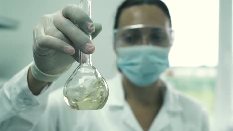 Girl-lab-assistant-stirs-the-liquid-in-a-flask