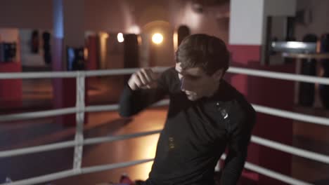 Slim-fit,-attractive-guy-boxer-is-engaged-in-the-ring,-preparing-for-the-first-fight,-concentrating-on-the-strokes.-Slow-motion-shooting-close-up