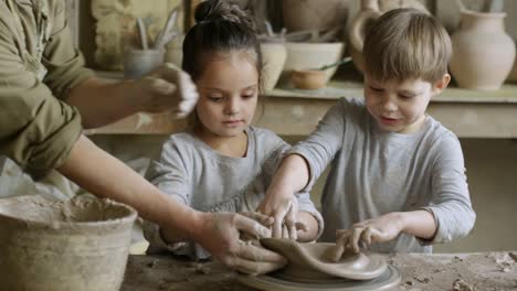 Ayudar-a-los-niños-hacer-cerámica-en-la-clase-artesanal