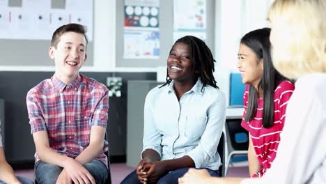 Grupo-de-estudiantes-de-secundaria-teniendo-una-discusión-Informal-con-la-profesora-en-clase