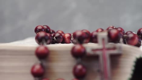 Bible-and-the-crucifix-beads-on-a-red-wooden-table.-Beautiful-background.-Religion-concept-close-up