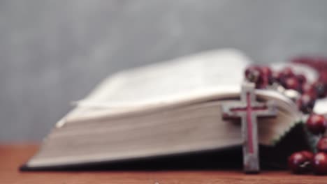 Bible-and-the-crucifix-beads-on-a-red-wooden-table.-Beautiful-background.-Religion-concept-close-up