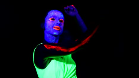 Woman-with-UV-face-paint,-glowing-clothing-dancing-fast-in-front-of-camera,-shoulder-face-shot.-Caucasian-woman.-.