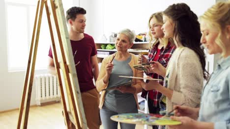 group-of-artists-discussing-painting-at-art-school