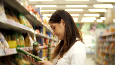 shopper-femenino-positivo-buscando-pasta-en-supermercado.