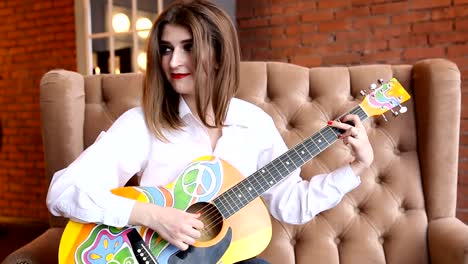 Woman-in-a-white-shirt-plays-guitar-in-hippie-style