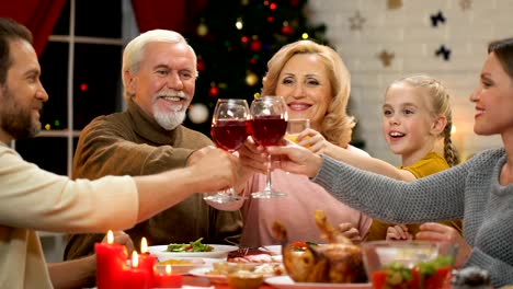 Family-raising-toast-at-Christmas-dinner,-tradition-to-get-together-for-holidays