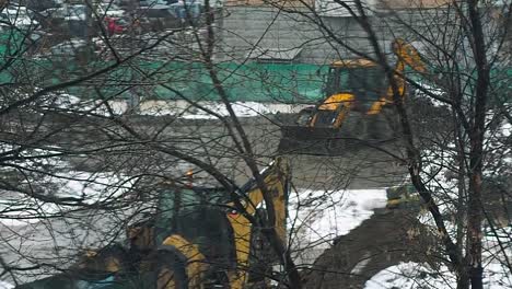 Pequeña-excavadora-empujes-de-suelo-en-un-sitio-de-construcción-en-invierno-bajo-la-nieve