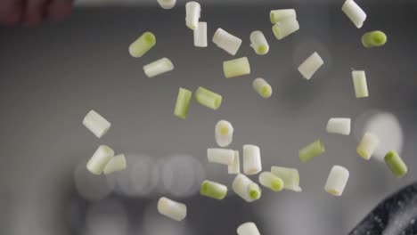 Falling-of-green-onion-into-the-frying-pan.-Slow-motion-240-fps