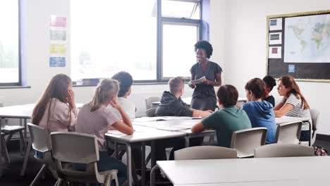 Weiblich-High-School-Lehrer-stehen-vom-Tisch-mit-Schülern-Unterricht