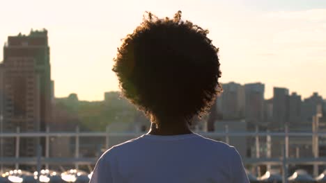 Junge-Afro-amerikanische-Frau-auf-Dach-sitzt-und-meditiert,-beobachtete-Stadtbild