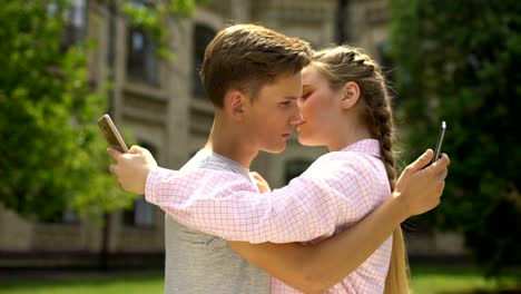 Couple-using-phone-while-hugging,-addiction-to-social-networking-concept