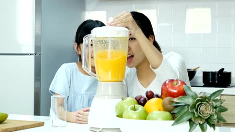 Madre-y-usando-poco-jugo-de-licuadora-en-la-cocina.-Ellos-haciendo-jugo-de-naranja-para-beber.-Personas-con-estilo-de-vida-y-el-concepto-saludable.