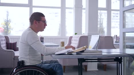 e-business-of-handicapped,-Successful-disabled-man-spectacled-on-wheelchair-works-on-smart-laptop-computer-during-remote-business-management